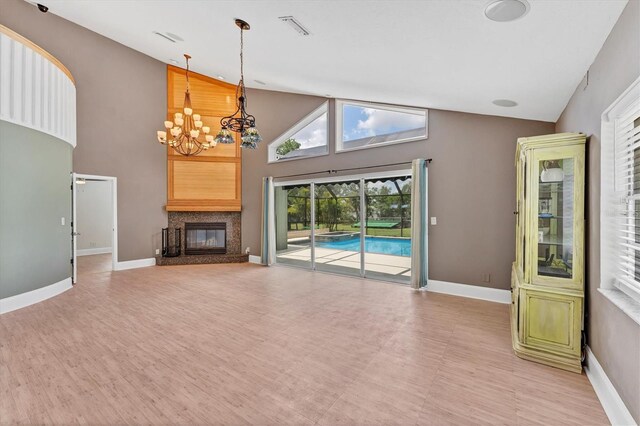 919 Palm View Way, Sarasota, FL 34240 - unfurnished living room featuring a chandelier, high vaulted ceiling, baseboards, and a glass covered fireplace