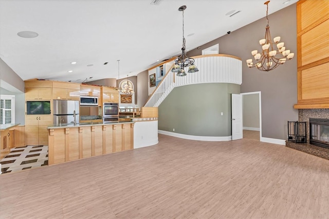 919 Palm View Way, Sarasota, FL 34240 - kitchen featuring a chandelier, appliances with stainless steel finishes, light brown cabinetry, a kitchen island, and high vaulted ceiling