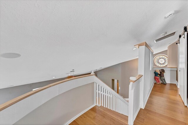 919 Palm View Way, Sarasota, FL 34240 - hall featuring an upstairs landing, wood finished floors, a barn door, baseboards, and a textured ceiling