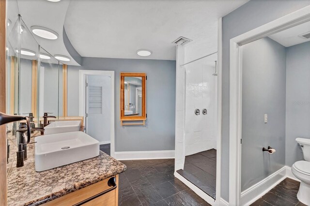919 Palm View Way, Sarasota, FL 34240 - bathroom with baseboards, a tile shower, toilet, and double vanity