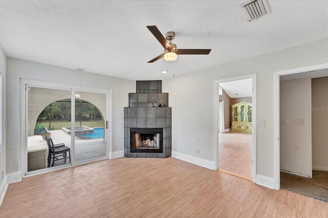 919 Palm View Way, Sarasota, FL 34240 - unfurnished living room featuring a ceiling fan, a tiled fireplace, light wood finished floors, and baseboards