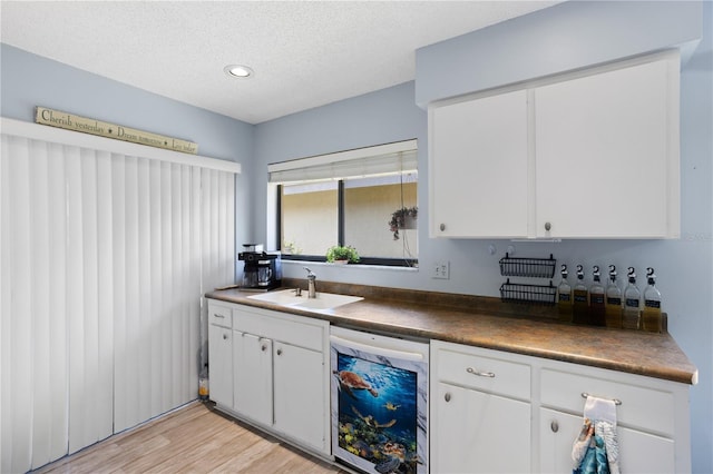 4203 Carriage Dr Unit 27, Sarasota, FL 34241 - kitchen with a sink, white dishwasher, dark countertops, white cabinetry, and light wood-type flooring