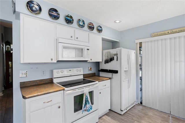 4203 Carriage Dr Unit 27, Sarasota, FL 34241 - kitchen with white appliances, dark countertops, light wood-style floors, white cabinetry, and a textured ceiling