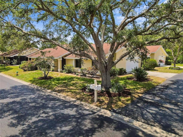 4203 Carriage Dr Unit 27, Sarasota, FL 34241 - view of front of home with concrete driveway, stucco siding, a front lawn, and an attached garage