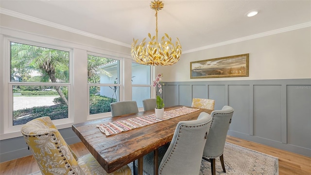 4665 Pine Harrier Dr, Sarasota, FL 34231 - dining space featuring a chandelier, a decorative wall, crown molding, light wood-style floors, and wainscoting
