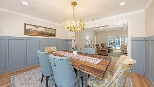 4665 Pine Harrier Dr, Sarasota, FL 34231 - dining space with a chandelier, light wood finished floors, a decorative wall, crown molding, and wainscoting