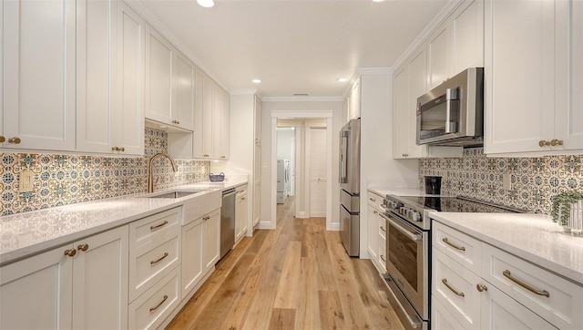 4665 Pine Harrier Dr, Sarasota, FL 34231 - kitchen with stainless steel appliances, a sink, white cabinets, washer / clothes dryer, and crown molding