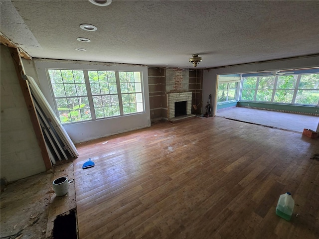 2905 Sunset Rd, Melbourne, FL 32904 - unfurnished living room featuring a textured ceiling, hardwood / wood-style floors, and a fireplace