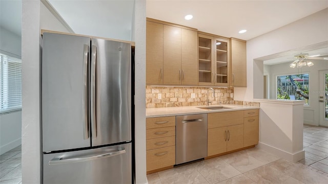 755 Edgemere Ln, Sarasota, FL 34242 - kitchen with stainless steel appliances, a sink, light countertops, backsplash, and glass insert cabinets