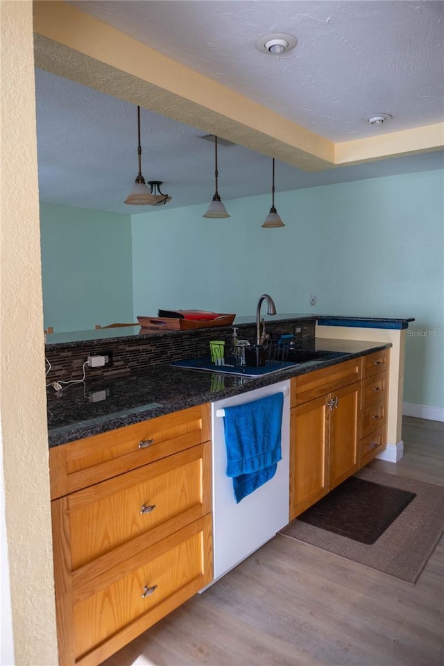 1004 65th Ave W, Bradenton, FL 34207 - kitchen with white dishwasher, hanging light fixtures, light wood-style floors, dark stone counters, and a textured ceiling