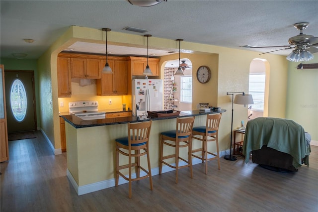 1004 65th Ave W, Bradenton, FL 34207 - kitchen featuring white appliances, arched walkways, dark wood finished floors, ceiling fan, and a breakfast bar
