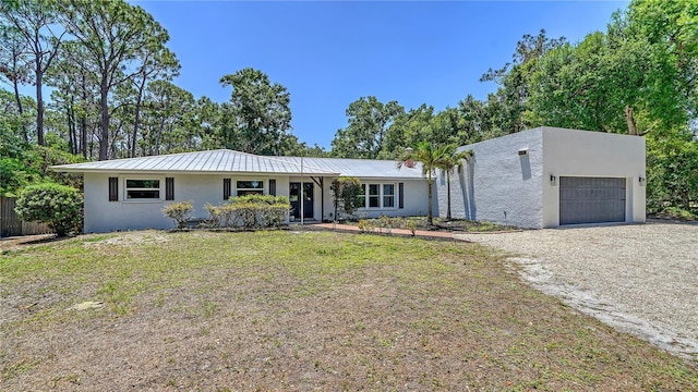 6990 Richardson Rd, Sarasota, FL 34240 - view of front of home with stucco siding, an attached garage, dirt driveway, and metal roof