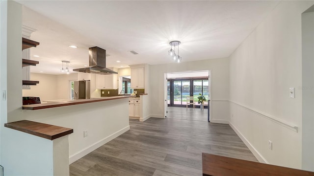 6990 Richardson Rd, Sarasota, FL 34240 - kitchen featuring island exhaust hood, wood finished floors, white cabinets, pendant lighting, and recessed lighting