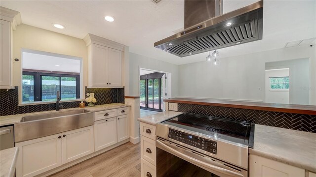 6990 Richardson Rd, Sarasota, FL 34240 - kitchen with stainless steel range with electric stovetop, wall chimney range hood, a sink, tasteful backsplash, and healthy amount of natural light