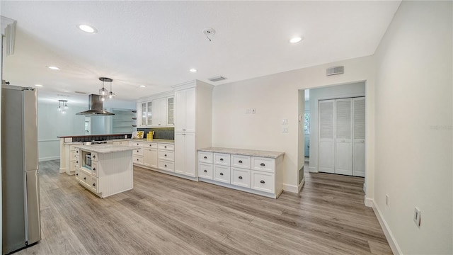6990 Richardson Rd, Sarasota, FL 34240 - kitchen with stainless steel refrigerator, island exhaust hood, white cabinets, glass insert cabinets, and recessed lighting