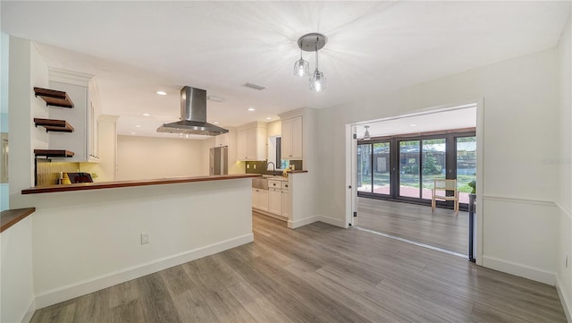 6990 Richardson Rd, Sarasota, FL 34240 - kitchen with exhaust hood, light wood finished floors, white cabinetry, baseboards, and recessed lighting