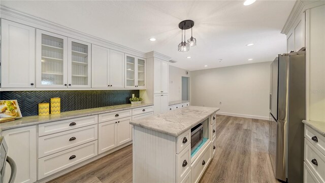 6990 Richardson Rd, Sarasota, FL 34240 - kitchen featuring stainless steel appliances, tasteful backsplash, white cabinetry, light wood finished floors, and light stone counters