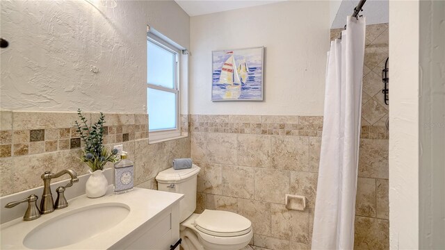 6990 Richardson Rd, Sarasota, FL 34240 - bathroom with tile walls, toilet, vanity, a shower with curtain, and a wainscoted wall