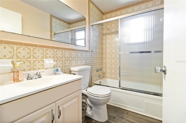 3102 SE 34th Ave, Okeechobee, FL 34974 - bathroom featuring wood finished floors, combined bath / shower with glass door, vanity, toilet, and tile walls