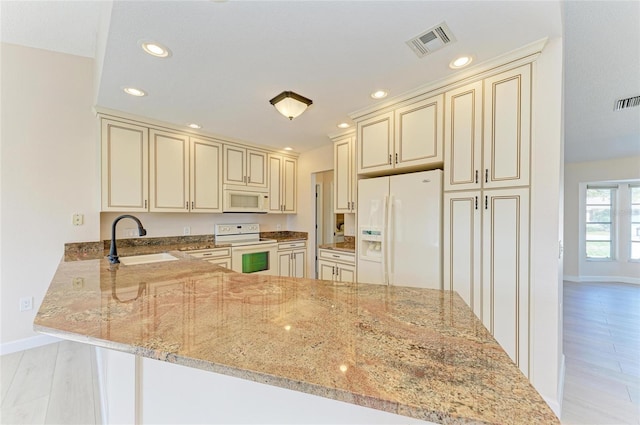 645 Liberty St, Englewood, FL 34223 - kitchen with cream cabinetry, white appliances, a sink, light stone counters, and recessed lighting