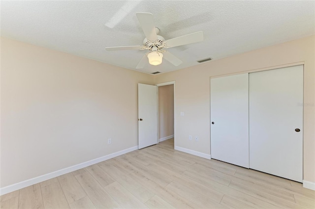 645 Liberty St, Englewood, FL 34223 - unfurnished bedroom featuring light wood-style floors, baseboards, a ceiling fan, a closet, and a textured ceiling