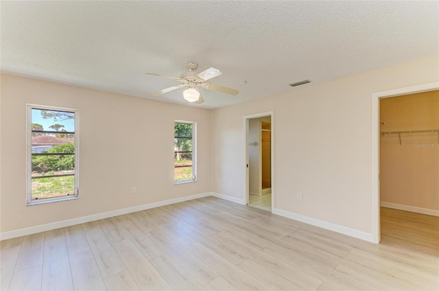 645 Liberty St, Englewood, FL 34223 - unfurnished bedroom featuring a spacious closet, light wood finished floors, a textured ceiling, a closet, and a ceiling fan