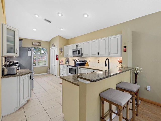 8222 Haven Harbour Way, Bradenton, FL 34212 - kitchen featuring stainless steel appliances, a breakfast bar area, a peninsula, baseboards, and dark stone counters