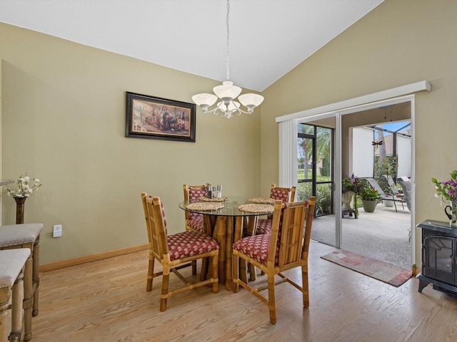 8222 Haven Harbour Way, Bradenton, FL 34212 - dining space featuring light wood-style flooring, a chandelier, a wood stove, baseboards, and high vaulted ceiling
