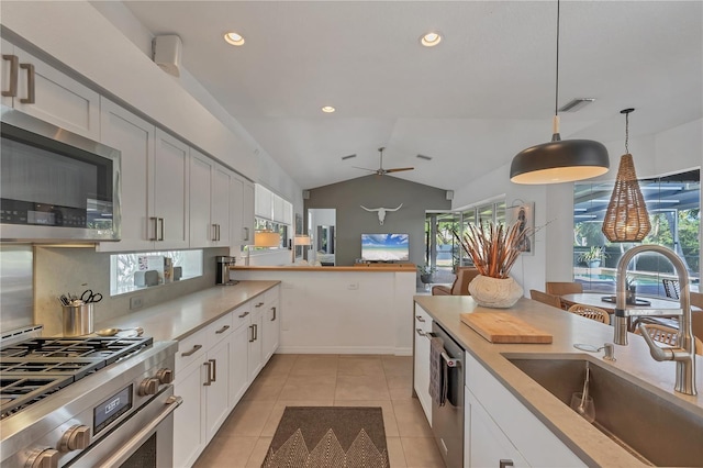 4505 Camino Real, Sarasota, FL 34231 - kitchen with appliances with stainless steel finishes, a sink, light countertops, light tile patterned floors, and lofted ceiling