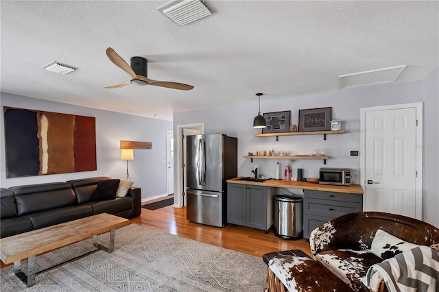 4505 Camino Real, Sarasota, FL 34231 - living room featuring light wood-type flooring, a textured ceiling, a ceiling fan, attic access, and baseboards