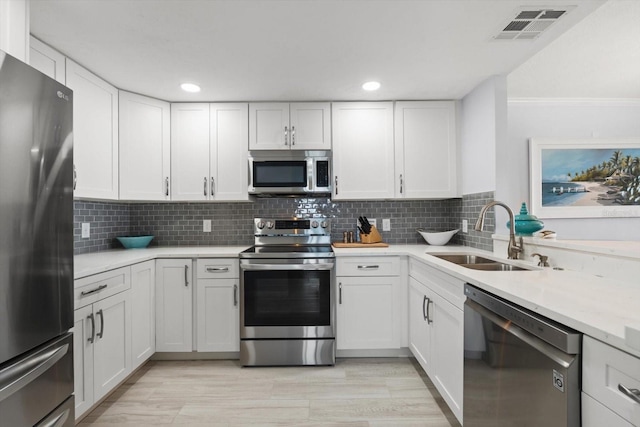 1255 E Peppertree Dr Unit 507, Sarasota, FL 34242 - kitchen with appliances with stainless steel finishes, a sink, light countertops, white cabinetry, and decorative backsplash