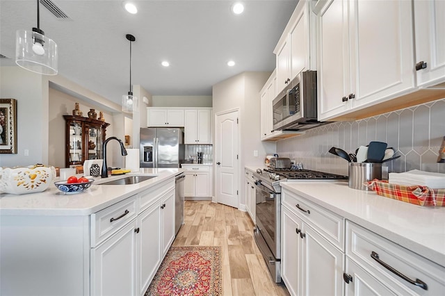 2625 Star Apple Way, Sarasota, FL 34240 - kitchen with stainless steel appliances, a sink, white cabinetry, tasteful backsplash, and light wood-type flooring