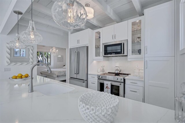 643 Calle Del Otono, Sarasota, FL 34242 - kitchen with appliances with stainless steel finishes, a chandelier, a sink, beamed ceiling, and white cabinetry