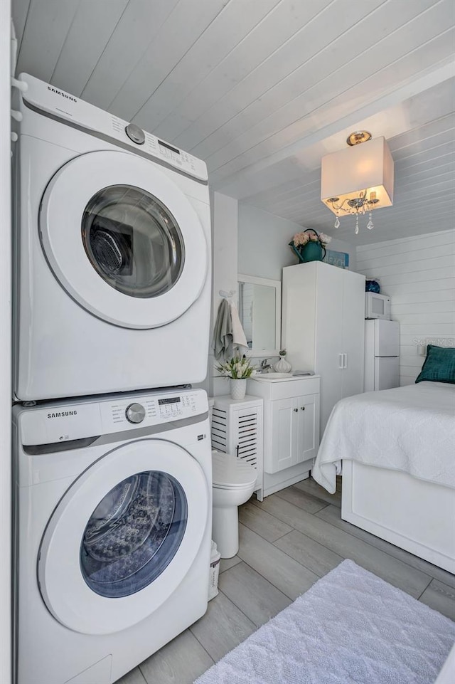 643 Calle Del Otono, Sarasota, FL 34242 - laundry room with stacked washer and clothes dryer, light wood-style flooring, and wooden ceiling