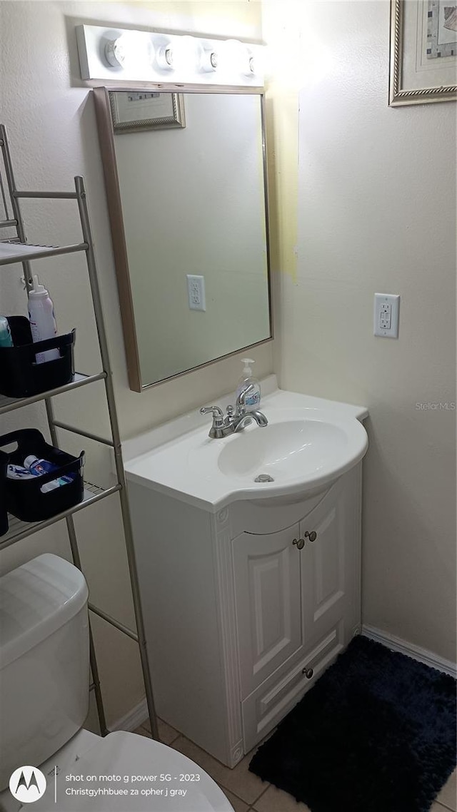 half bathroom with toilet, vanity, and tile patterned floors