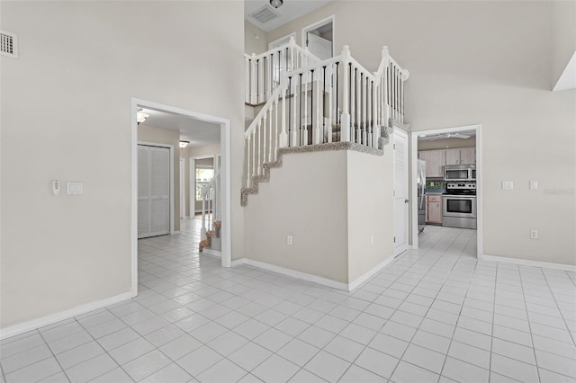 5310 SW 25th Ct, Cape Coral, FL 33914 - empty room featuring a towering ceiling, baseboards, light tile patterned floors, a ceiling fan, and stairway