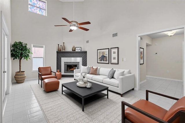 5310 SW 25th Ct, Cape Coral, FL 33914 - living room featuring light tile patterned floors, a towering ceiling, ceiling fan, a warm lit fireplace, and baseboards