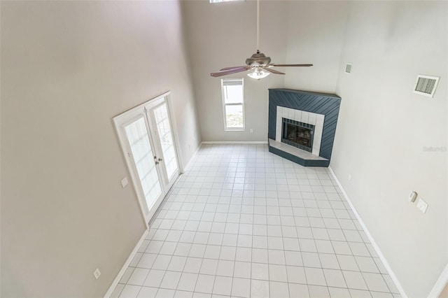 5310 SW 25th Ct, Cape Coral, FL 33914 - unfurnished living room with light tile patterned floors, a high ceiling, a ceiling fan, baseboards, and a tiled fireplace