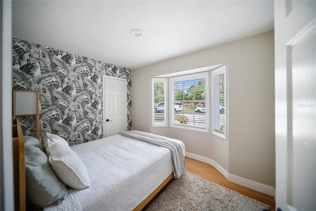 3810 Hidden River Rd, Sarasota, FL 34240 - bedroom featuring an accent wall, wallpapered walls, baseboards, and light wood-style floors
