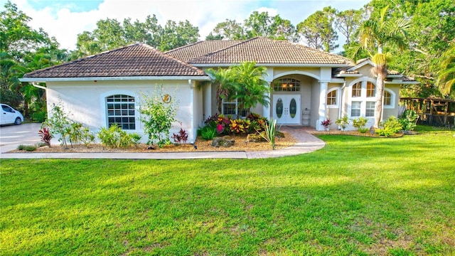 950 Trotter St, Nokomis, FL 34275 - mediterranean / spanish home featuring french doors, a front lawn, stucco siding, and a tiled roof