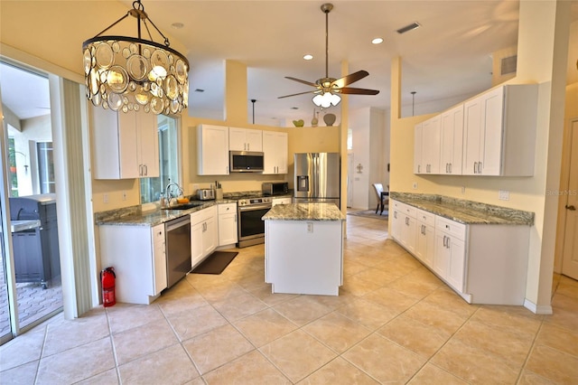 950 Trotter St, Nokomis, FL 34275 - kitchen with appliances with stainless steel finishes, a sink, white cabinetry, a kitchen island, and light stone countertops