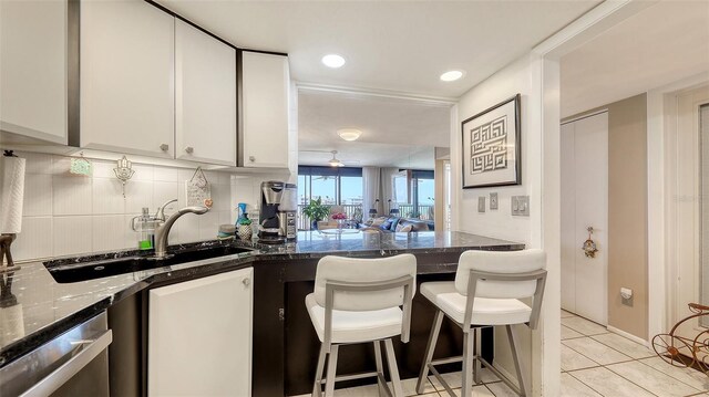 2045 Gulf Of Mexico Dr Unit M1-514, Longboat Key, FL 34228 - kitchen with white cabinets, a kitchen breakfast bar, a sink, dark stone counters, and light tile patterned floors