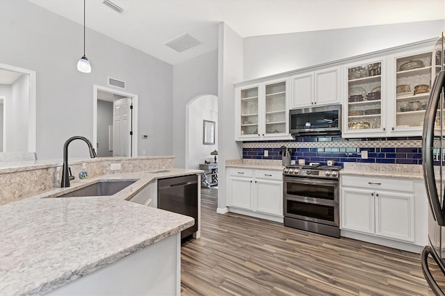 12755 Rainwashed Loop, Parrish, FL 34219 - kitchen with stainless steel appliances, a sink, decorative backsplash, arched walkways, and white cabinets