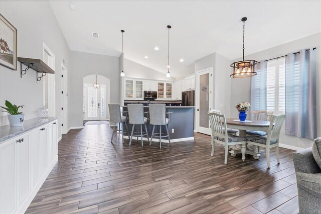 12755 Rainwashed Loop, Parrish, FL 34219 - dining space featuring a chandelier, vaulted ceiling, arched walkways, baseboards, and dark wood-type flooring