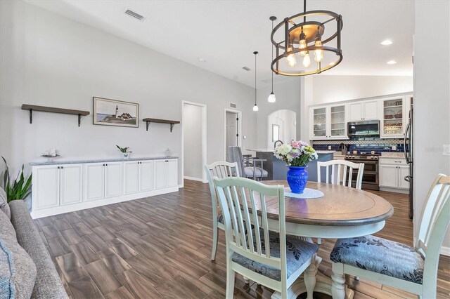 12755 Rainwashed Loop, Parrish, FL 34219 - dining space featuring a chandelier, dark wood-type flooring, vaulted ceiling, arched walkways, and baseboards