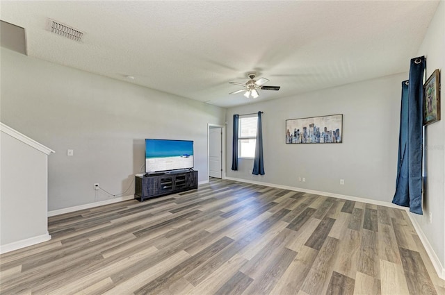 1721 Palm Warbler Ln, Ruskin, FL 33570 - unfurnished living room featuring ceiling fan, wood finished floors, baseboards, and a textured ceiling