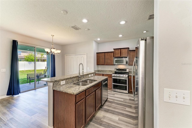 1721 Palm Warbler Ln, Ruskin, FL 33570 - kitchen with appliances with stainless steel finishes, a sink, light wood finished floors, a textured ceiling, and a chandelier