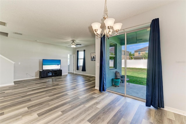 1721 Palm Warbler Ln, Ruskin, FL 33570 - unfurnished living room featuring wood finished floors, baseboards, a chandelier, a textured ceiling, and a ceiling fan