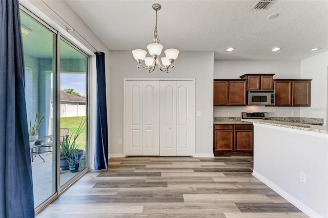 1721 Palm Warbler Ln, Ruskin, FL 33570 - kitchen with stainless steel microwave, stove, a chandelier, light wood-style flooring, and recessed lighting
