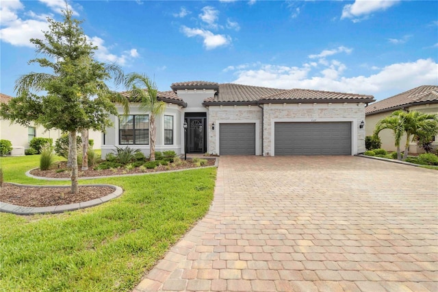 7327 Summerland Cv, Bradenton, FL 34202 - mediterranean / spanish-style home featuring a garage, decorative driveway, a front lawn, a tile roof, and stone siding